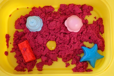 Bright kinetic sand and toys in yellow basin, top view