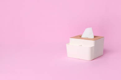 Holder with paper tissues on pink background. Space for text