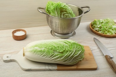 Fresh ripe Chinese cabbage and knife on white wooden kitchen table
