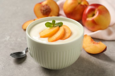 Delicious yogurt with fresh peach and mint on grey table, closeup