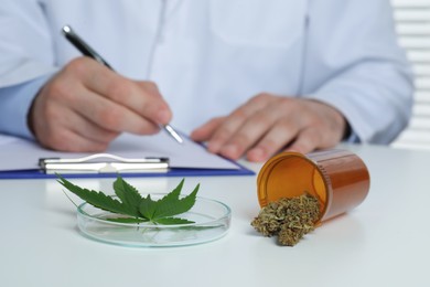 Doctor writing at table, focus on medical hemp
