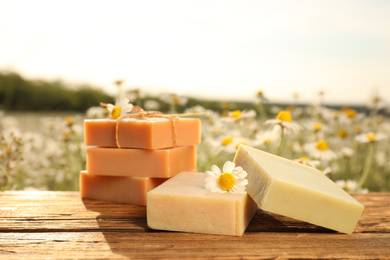 Chamomile soap bars on wooden table in field