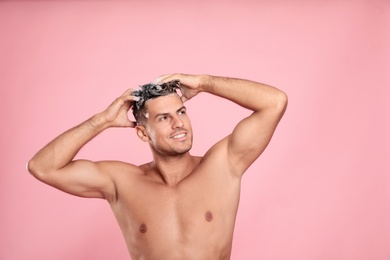 Handsome man washing hair on pink background