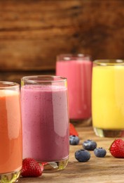 Glasses with different tasty smoothies on wooden table