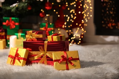 Beautiful Christmas gifts on furry carpet in room, space for text