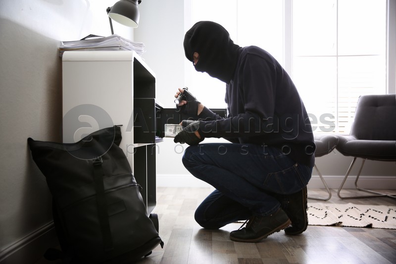 Thief taking money out of steel safe indoors