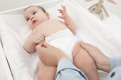 Photo of Mother changing baby's diaper, focus on hands
