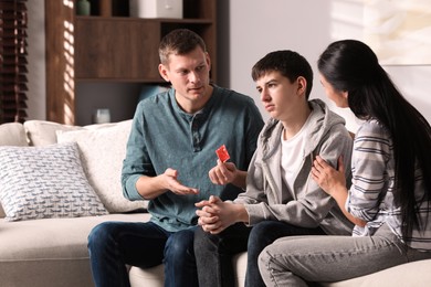 Photo of Parents talking with their teenage son about contraception at home. Sex education concept