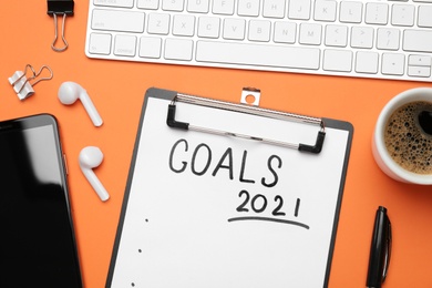 Paper with inscription 2021 Goals, new year items. Objects on orange background, flat lay