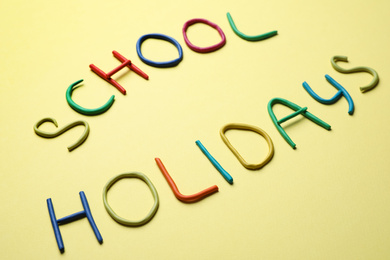 Photo of Text School Holidays made of modelling clay on yellow background
