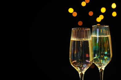 Glasses of champagne on black background, closeup. Space for text