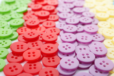 Many colorful plastic sewing buttons as background, closeup