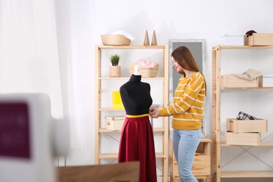 Photo of Fashion designer working with mannequin in studio. Creating new clothes