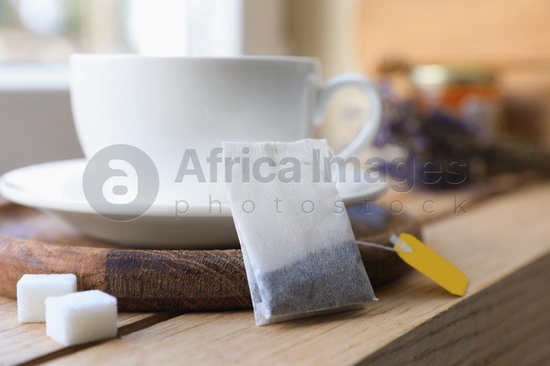 Tea bag and cup on wooden table indoors, closeup