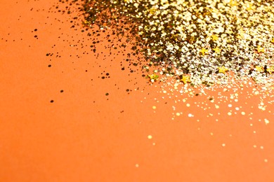 Shiny bright golden glitter on pale coral background, closeup. Space for text