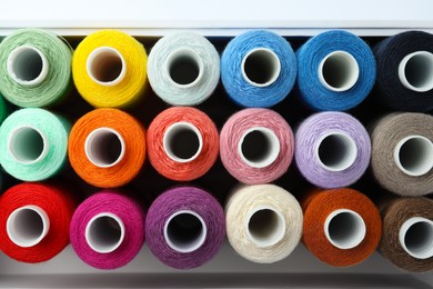 Set of different colorful sewing threads in container on white background, top view