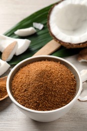 Natural coconut sugar in bowl on white wooden table