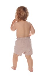 Photo of Cute baby in shorts learning to walk on white background, back view
