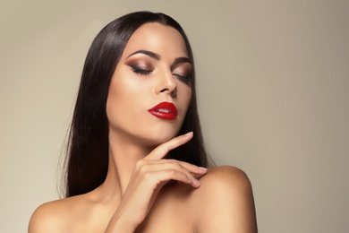 Portrait of beautiful young woman with red glossy lips on color background