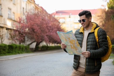 Happy male tourist with map on city street