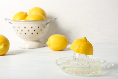 Ripe lemons and juicer on table against light background