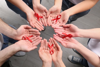 Group of people holding red awareness ribbons indoors, above view. World AIDS disease day