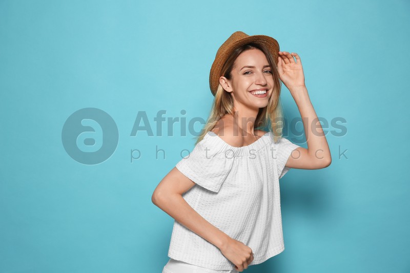 Beautiful young woman wearing straw hat on light blue background, space for text. Stylish headdress