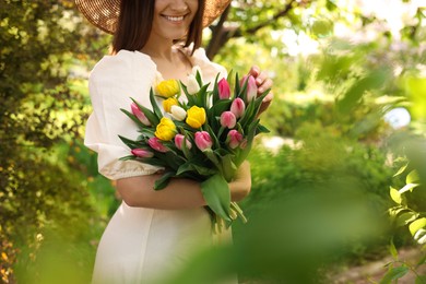Young woman with bouquet of tulips in park on sunny day, closeup