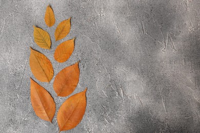 Flat lay composition of beautiful orange leaves on grey textured table. Space for text