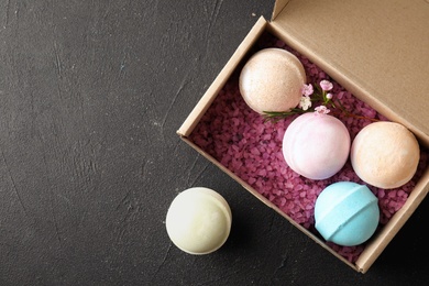 Photo of Carton box with bath bombs and space for text on black background, top view