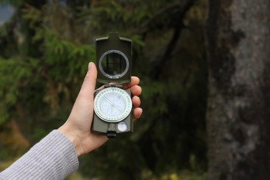 Woman using compass during hiking in forest, closeup