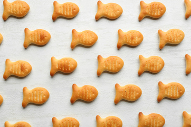 Delicious goldfish crackers on white table, flat lay