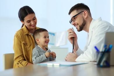 Mother and son visiting pediatrician in hospital. Doctor playing with little boy