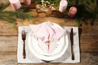 Stylish table setting with pink fabric napkin, beautiful decorative ring and festive decor on wooden background, flat lay