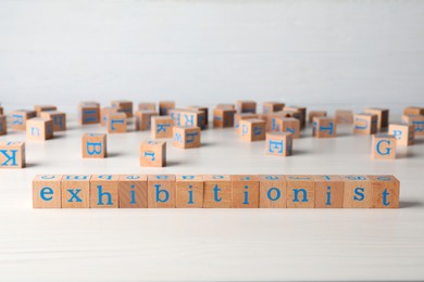 Word EXHIBITIONIST made with wooden cubes on white table