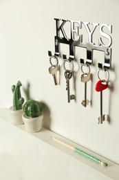 Metal key holder on light wall indoors