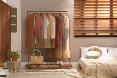 Garment bags with clothes hanging on rack in bedroom