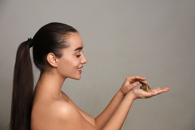 Photo of Beautiful young woman with snail on her hand against grey background