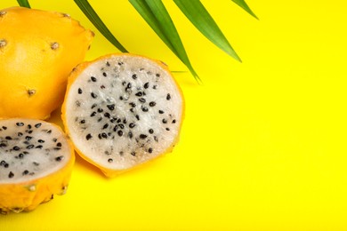 Delicious cut and whole dragon fruits (pitahaya) on yellow background, closeup. Space for text