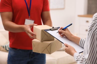 Woman signing for delivered parcels at home, closeup. Courier service