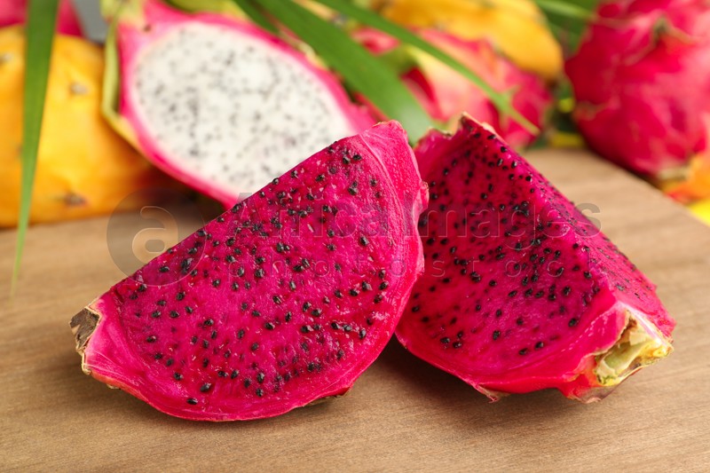 Delicious cut red pitahaya fruit on wooden board, closeup