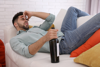 Young man suffering from hangover in room after party