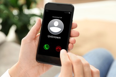 Woman declining incoming call from unknown caller indoors, closeup. Be careful - fraud