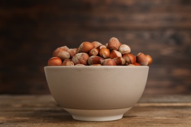 Ceramic bowl with acorns on wooden table. Cooking utensil
