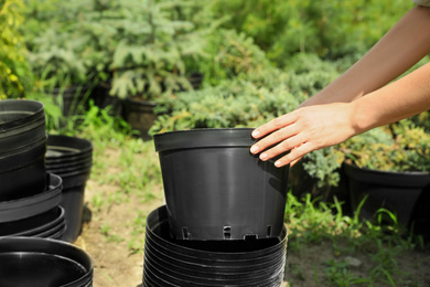 Woman with black pots for tree planting outdoors, closeup