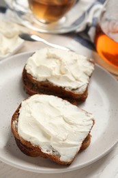 Photo of Bread with cream cheese on plate, closeup