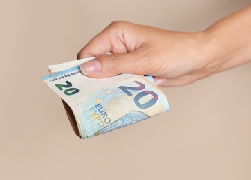 Woman with Euro banknotes on brown background, closeup