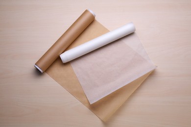 Rolls of baking paper on wooden table, flat lay