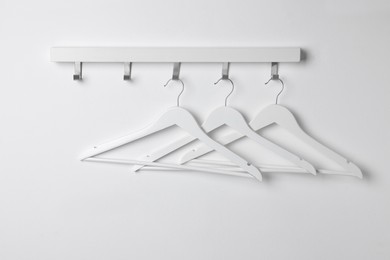 Photo of Rack with empty clothes hangers on white wall