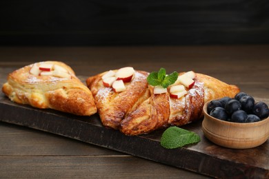 Photo of Fresh tasty puff pastry with blueberries, apples and mint served on wooden table
